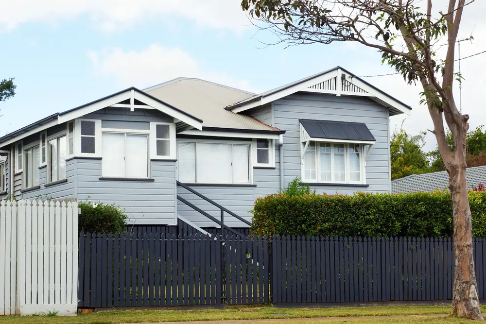 Queenslander-style home with blue-grey weatherboards and front garden